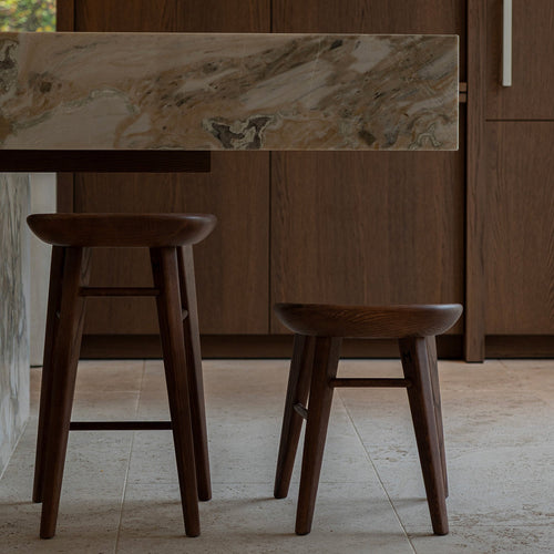 t4option0_0 | Ollie stool in walnut wood, minimalist design with soft curved seat and tapered legs.