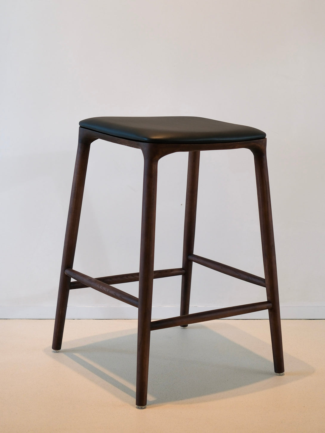 Mowelli bar stool with black leather seat and walnut wood frame, handcrafted Belgian design furniture for modern interiors