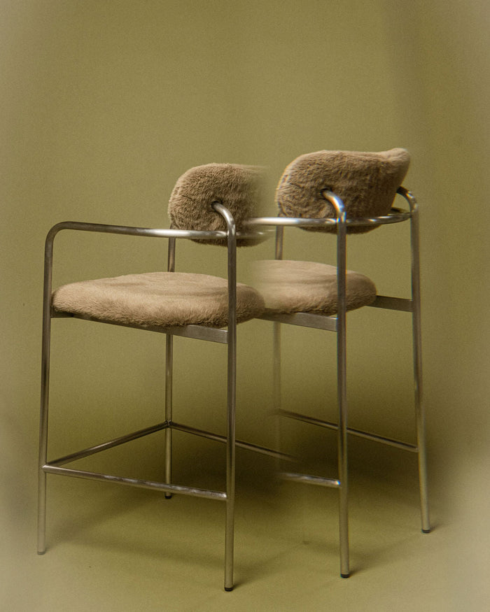 t4option0_1 | Coco bar chair in sage grey textured upholstery with a brushed stainless steel frame, shown in a minimal interior setting