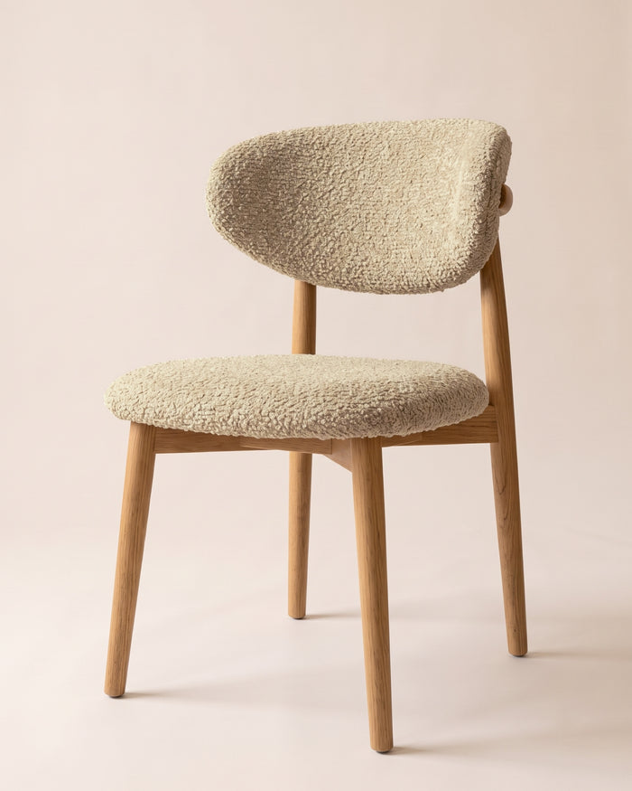 t4option0_4 | A modern wooden dining chair with a textured cream bouclé seat and curved backrest, set against a solid pale beige background.