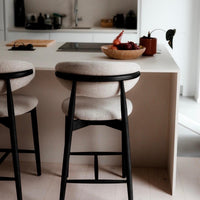 t4option0_2 | Pair of Mowelli Dianne bar stools with black wooden frame and light beige upholstery at a modern kitchen counter