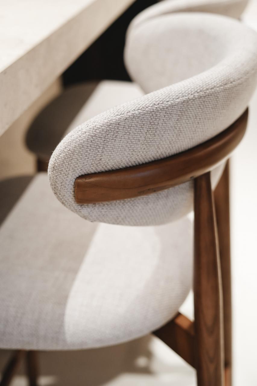 Close-up of the Mowelli Dianne bar stool in walnut wood with curved upholstered backrest