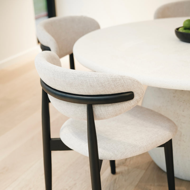 Close-up of Mowelli Dianne dining chair in black finish, showing curved backrest and textured fabric seat