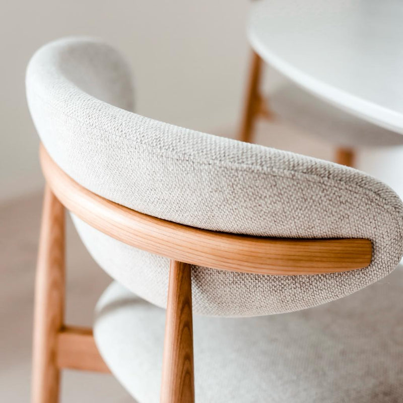Detailed shot of Mowelli Dianne dining chair in natural oak, highlighting the minimalist wooden armrest and natural texture