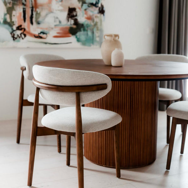 Dianne dining chairs by Mowelli in walnut wood paired with round walnut dining table for a cohesive look