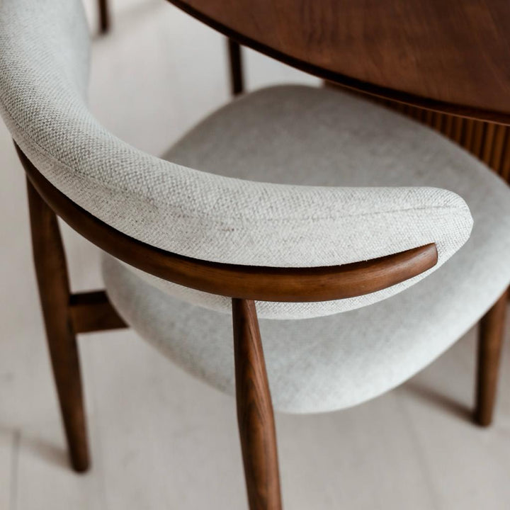Top view of Mowelli Dianne dining chair in walnut wood, featuring curved wooden armrest and soft upholstery