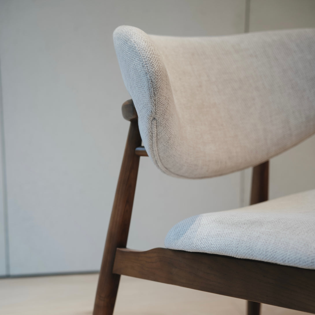 Close-up of Dianne lounge chair by Mowelli, showing ash wood legs and fabric texture detail