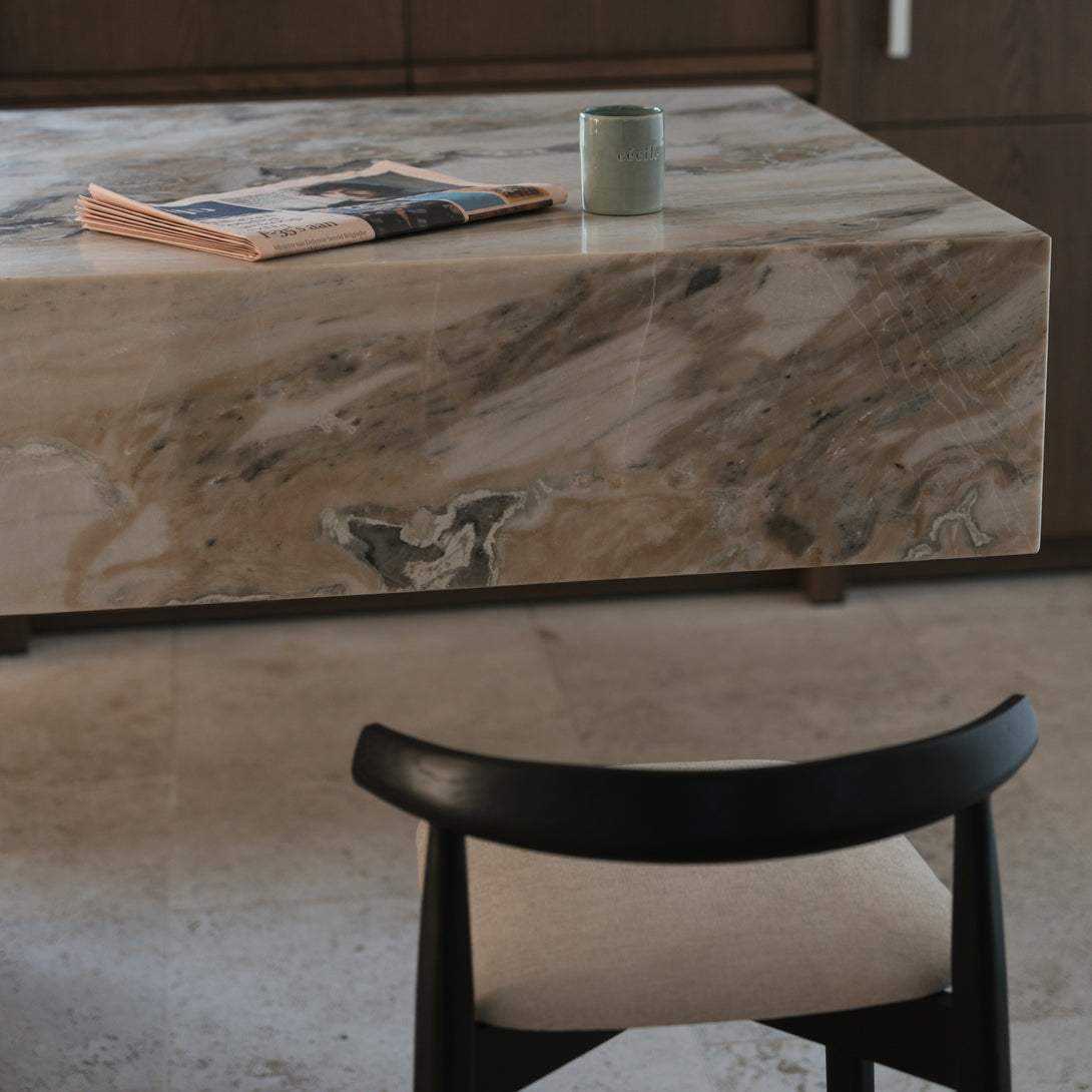 Top-down view of Ella bar stool by Mowelli in black wood and beige fabric, tucked under a marble countertop.
