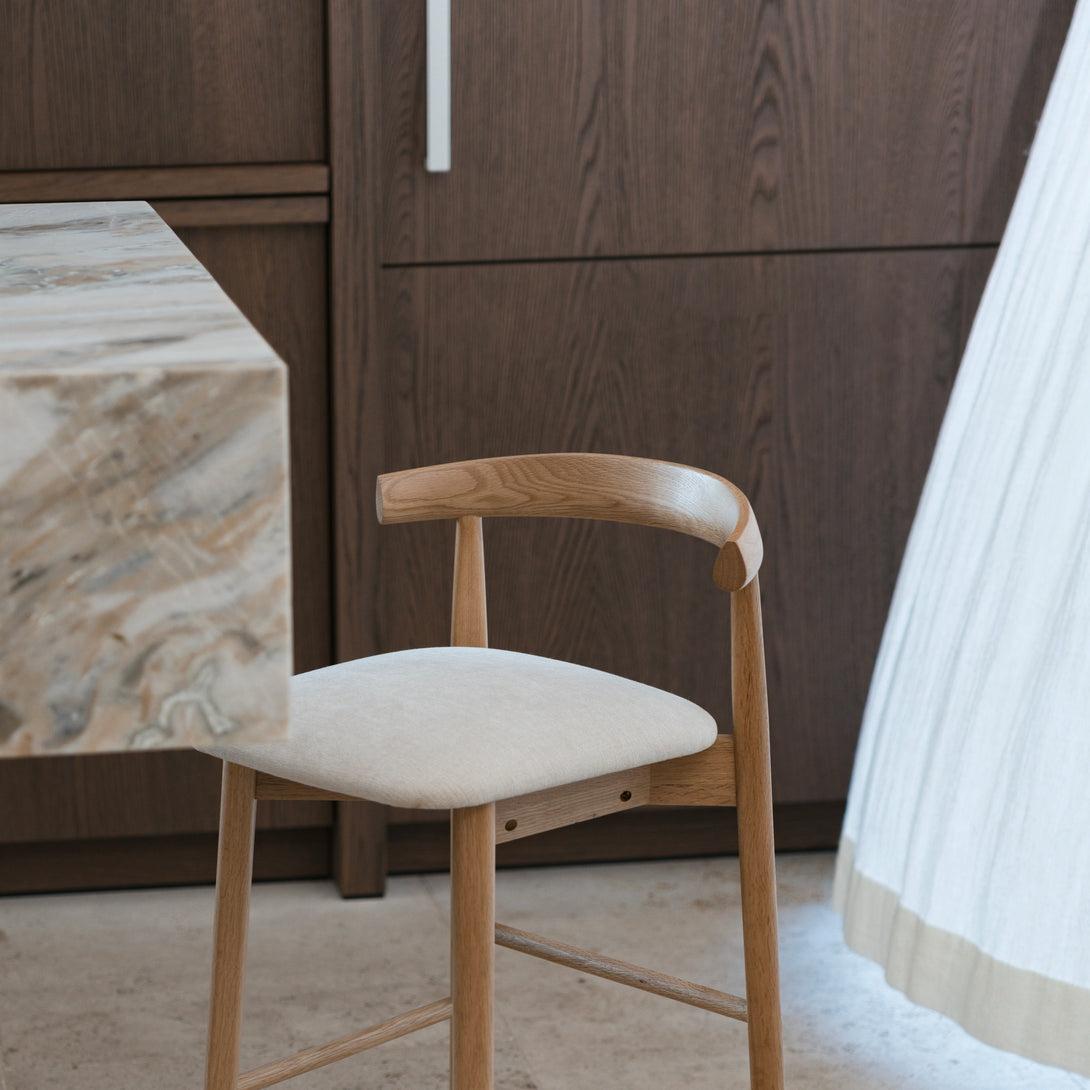 Natural oak version of Ella bar stool by Mowelli in light kitchen interior with neutral flooring.