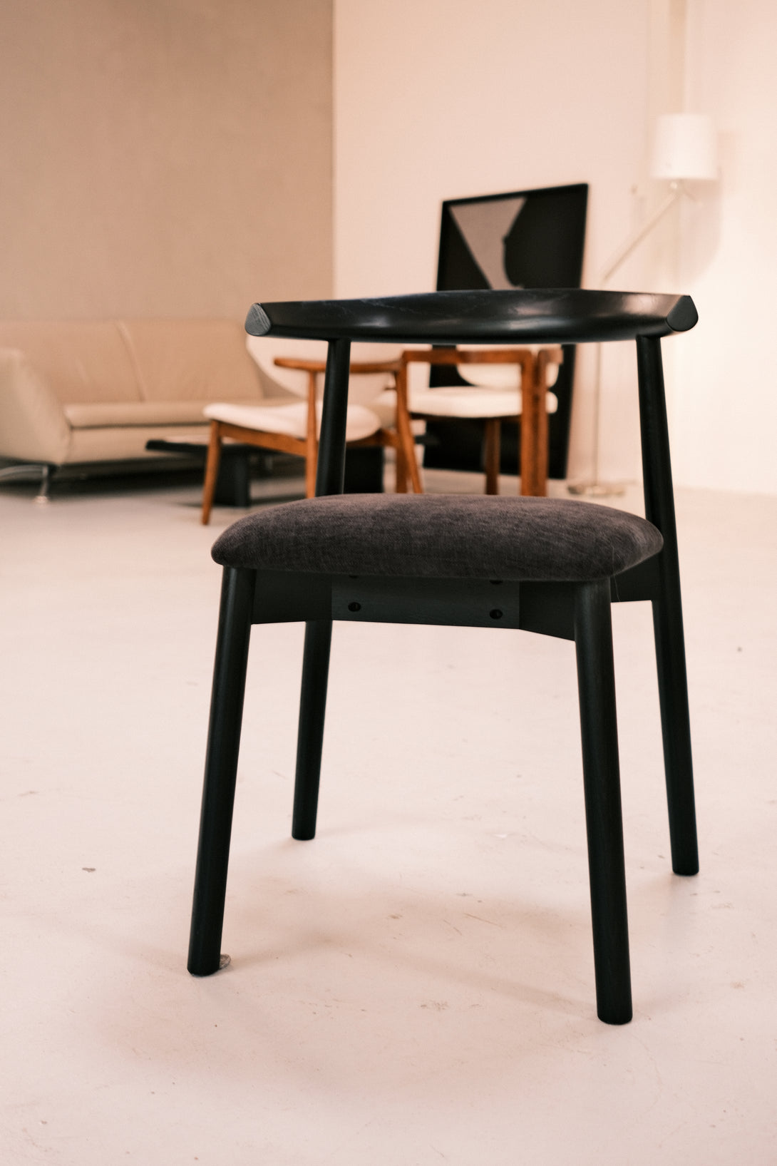Ella black dining chair by Mowelli with black seating, standing in a warehouse.
