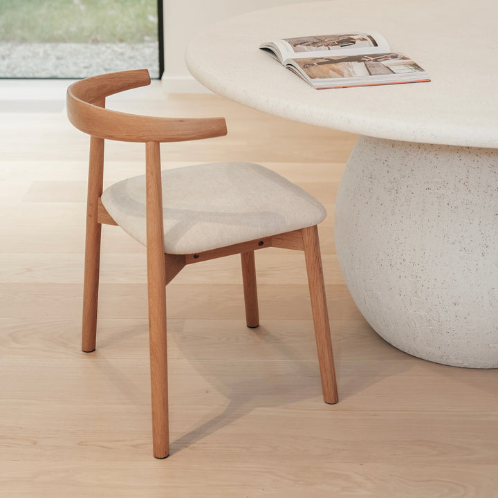 Natural oak Ella dining chair by Mowelli shown at a round white table, natural light setting.