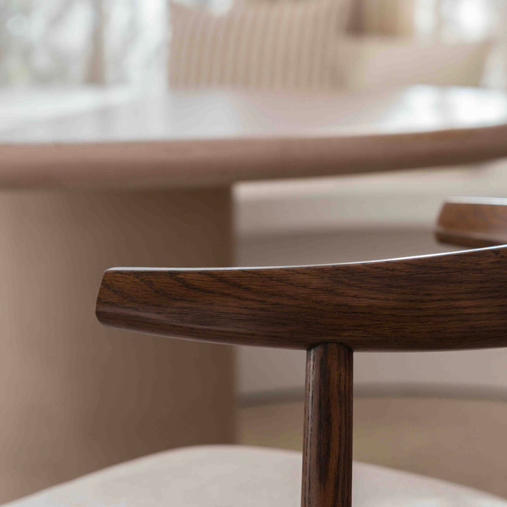 Elegant side profile of Ella dining chair by Mowelli in walnut finish, set in a modern interior.