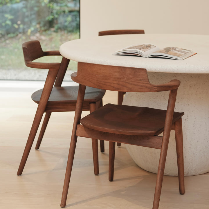 Jules wooden dining chairs by Mowelli standing at a contemporary round dining table, modern European furniture
