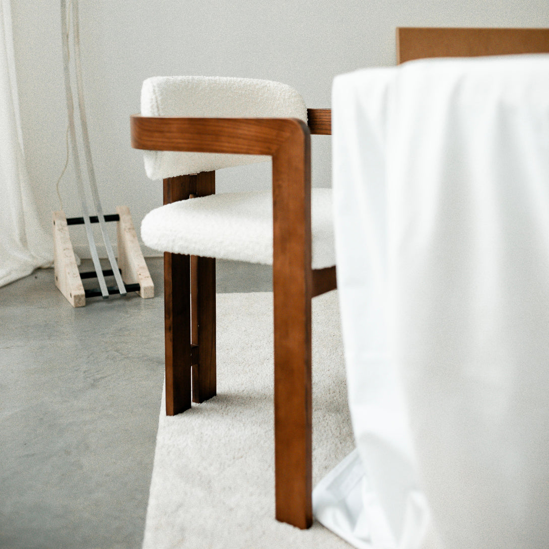 Side view of the Mila chair by Mowelli featuring a wooden frame and white bouclé seat, handcrafted in Europe.
