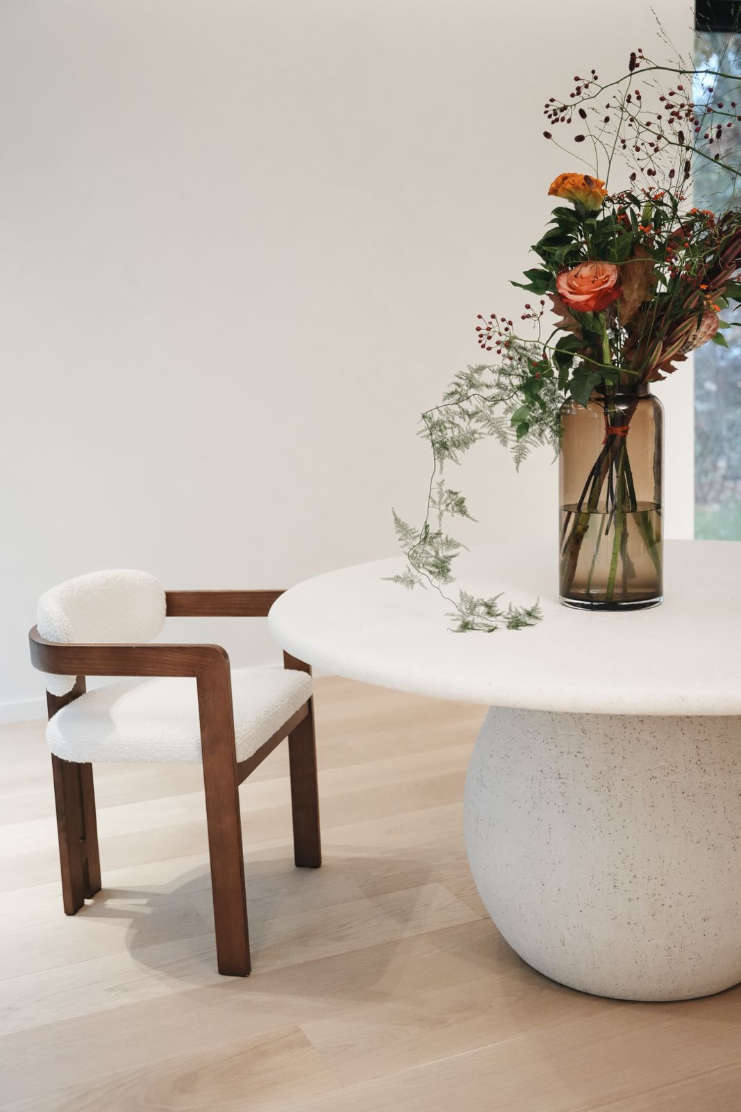 Mila dining chair by Mowelli in solid wood and white bouclé fabric, styled at a contemporary dining table. 