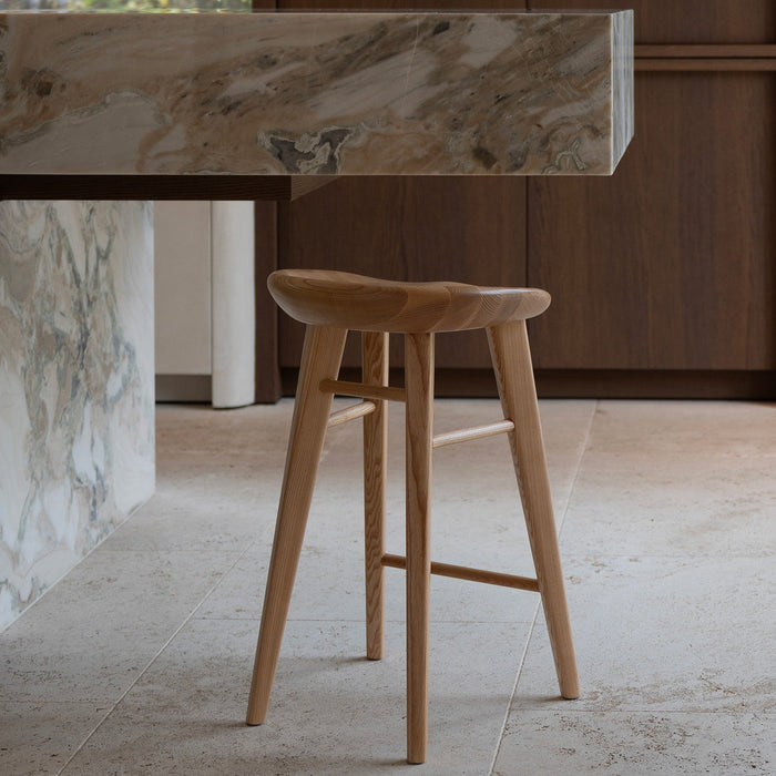 Ollie bar stool by Mowelli in naturel ash wood, styled at a kitchen counter with contemporary minimalist interiors.