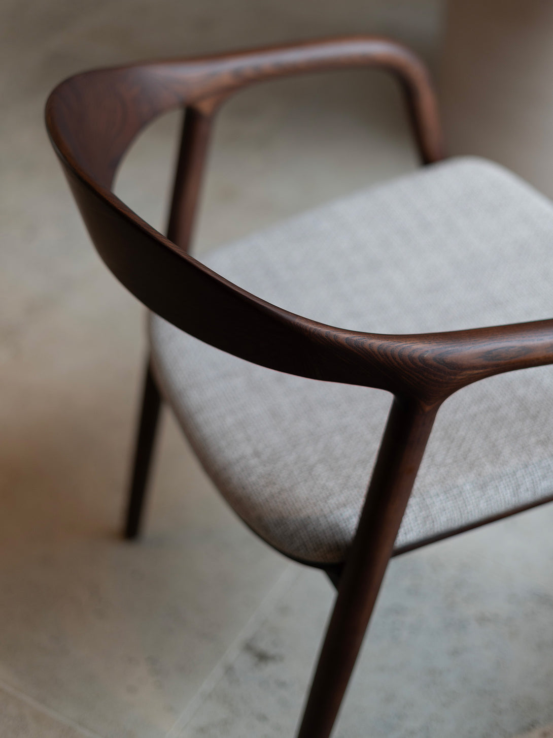 Nora comfort chair by Mowelli – stylish wooden chair in brown walnut with soft upholstered cushion seat, perfect for modern interiors.
