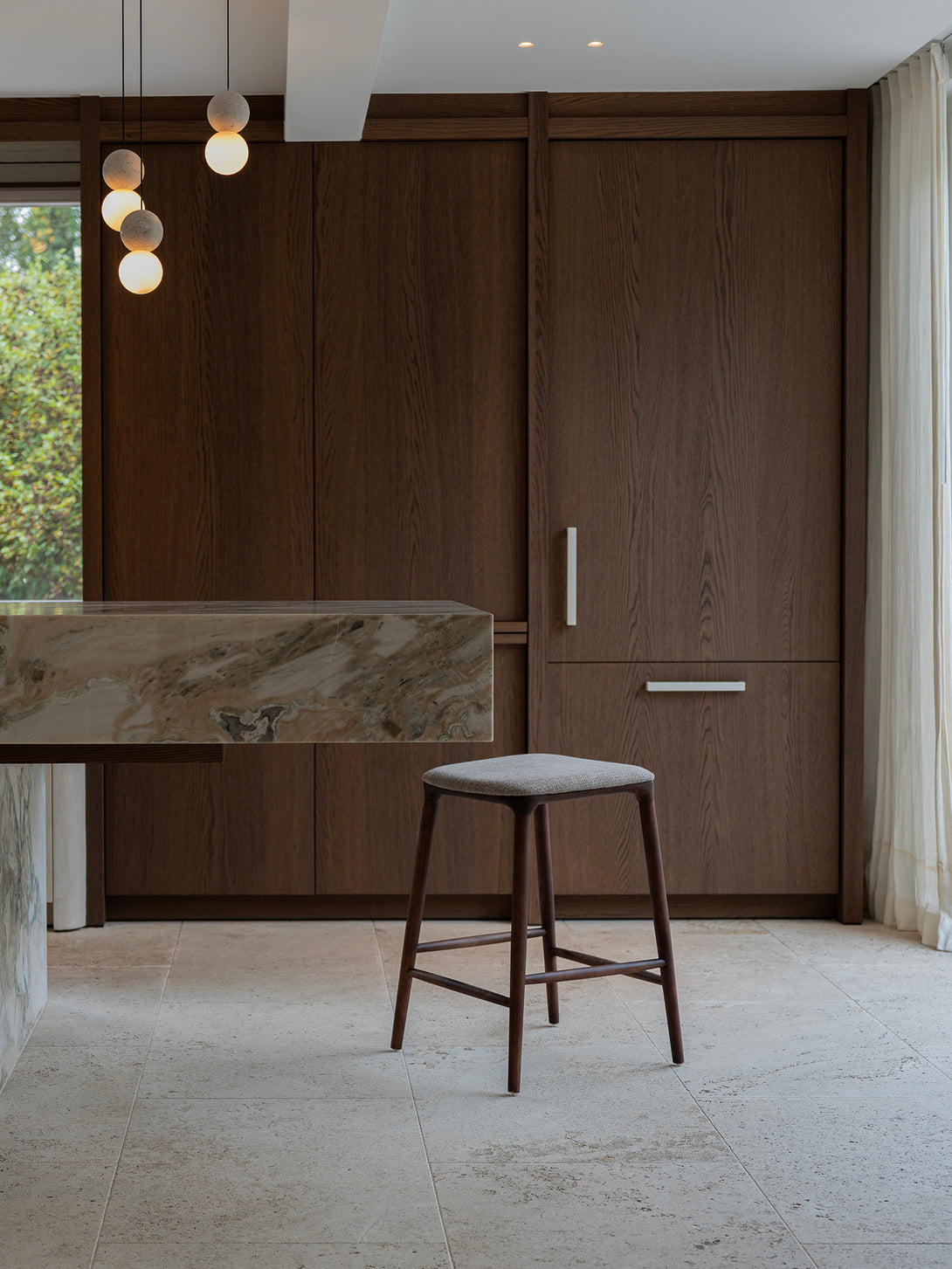 Mowelli Nora counter stool – stylish backless counterstool in brown walnut with soft upholstered cushion seat, ideal for kitchen counters and modern interiors.