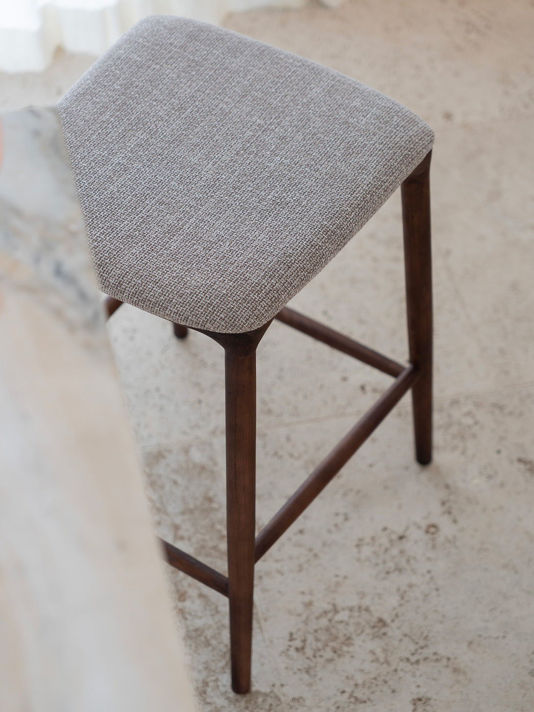 Mowelli Nora counter stool – stylish backless counterstool in brown walnut with soft upholstered cushion seat, ideal for kitchen counters and modern interiors.
