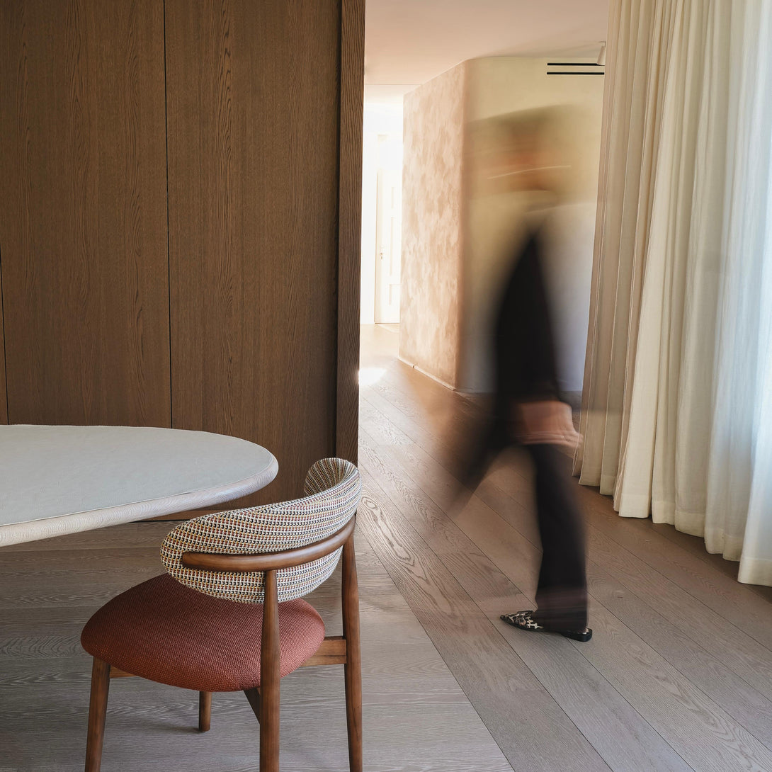 Back view of Mowelli x Rebo - Jeanne dining chair standing in a cosy setting with someone walking by