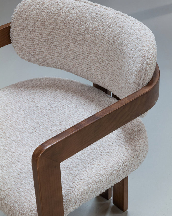Close-up of the Mila dining chair showcasing its walnut wood frame and textured upholstery.