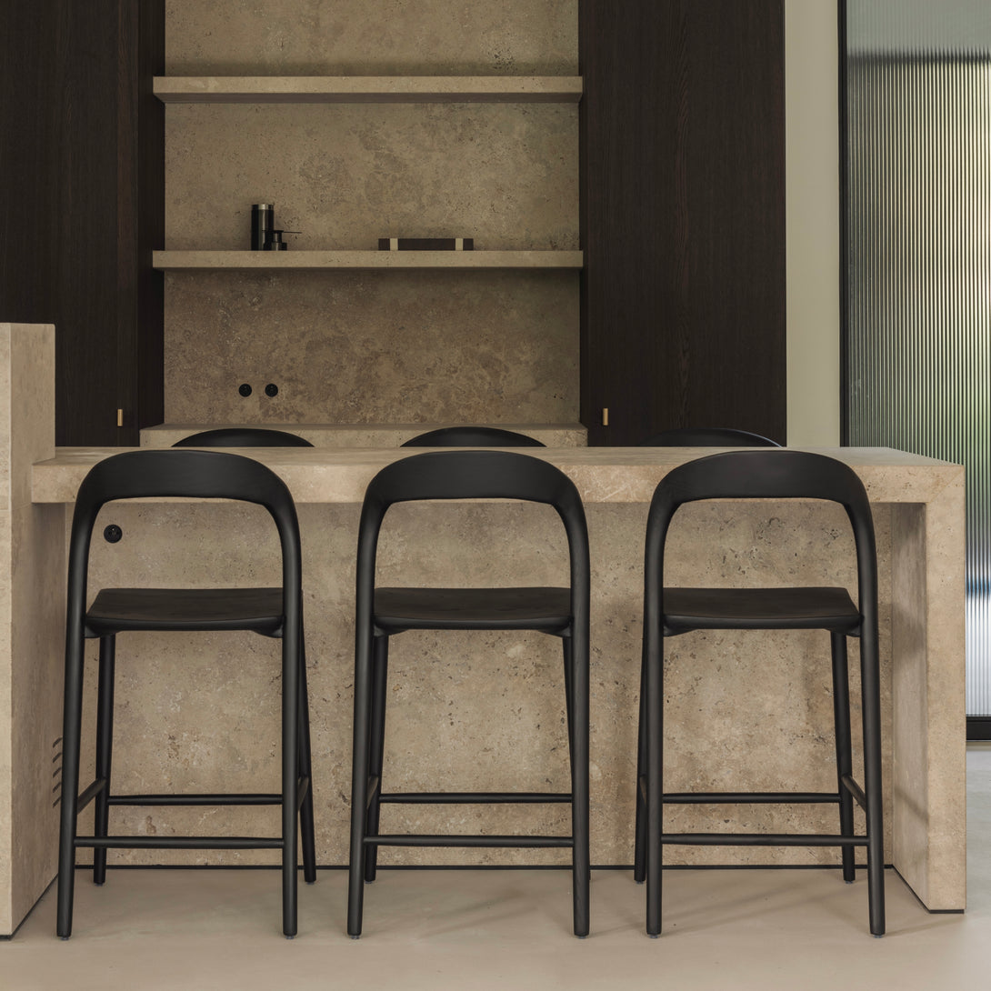 Three black Nora bar stools by Mowelli in minimalist interior – wooden design bar seating