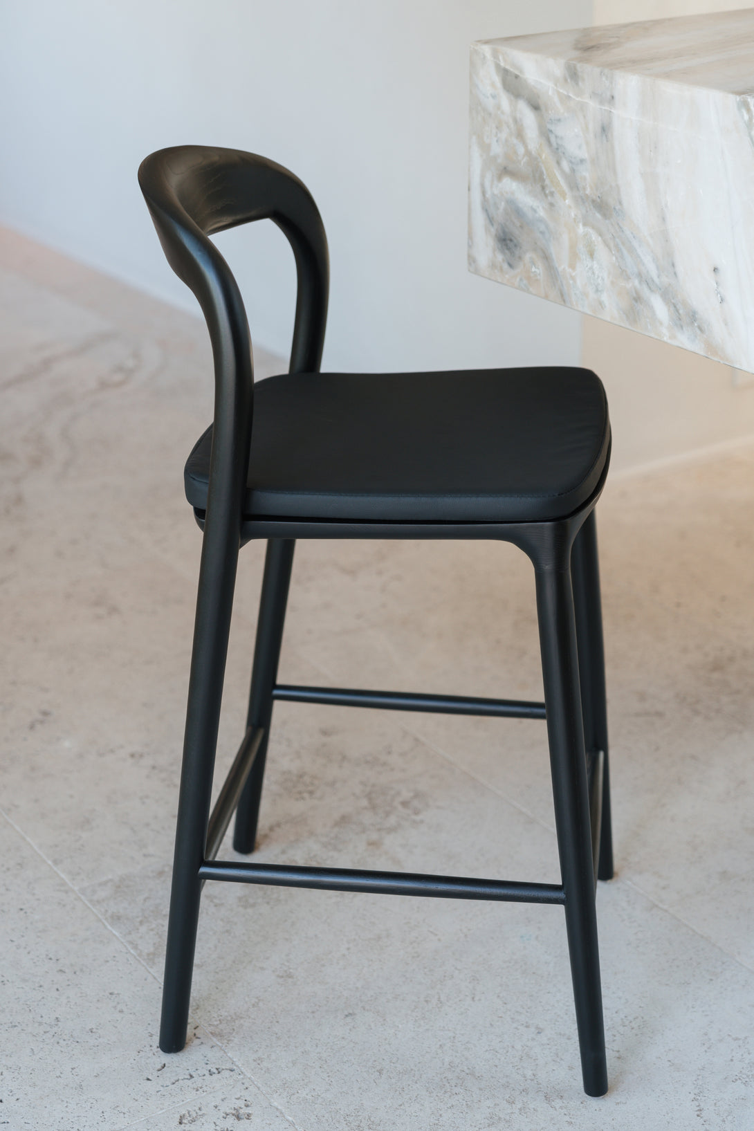 A charcoal black leather pillow by Mowelli on a black Nora bar stool