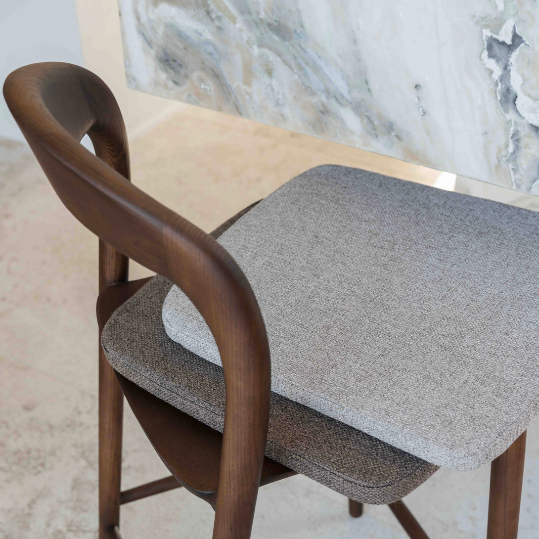 A soft greige fabric cushion laying on top of a mocha brown fabric cushion, presented on the Nora bar stool.