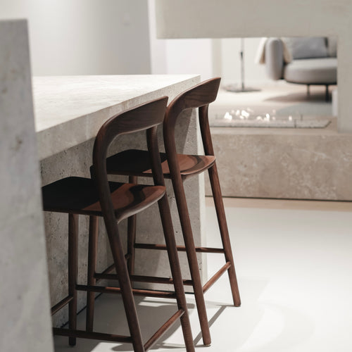 t4option0_0 | Two walnut Nora bar stools lined up at a concrete kitchen island – designer wooden bar chairs from Belgium