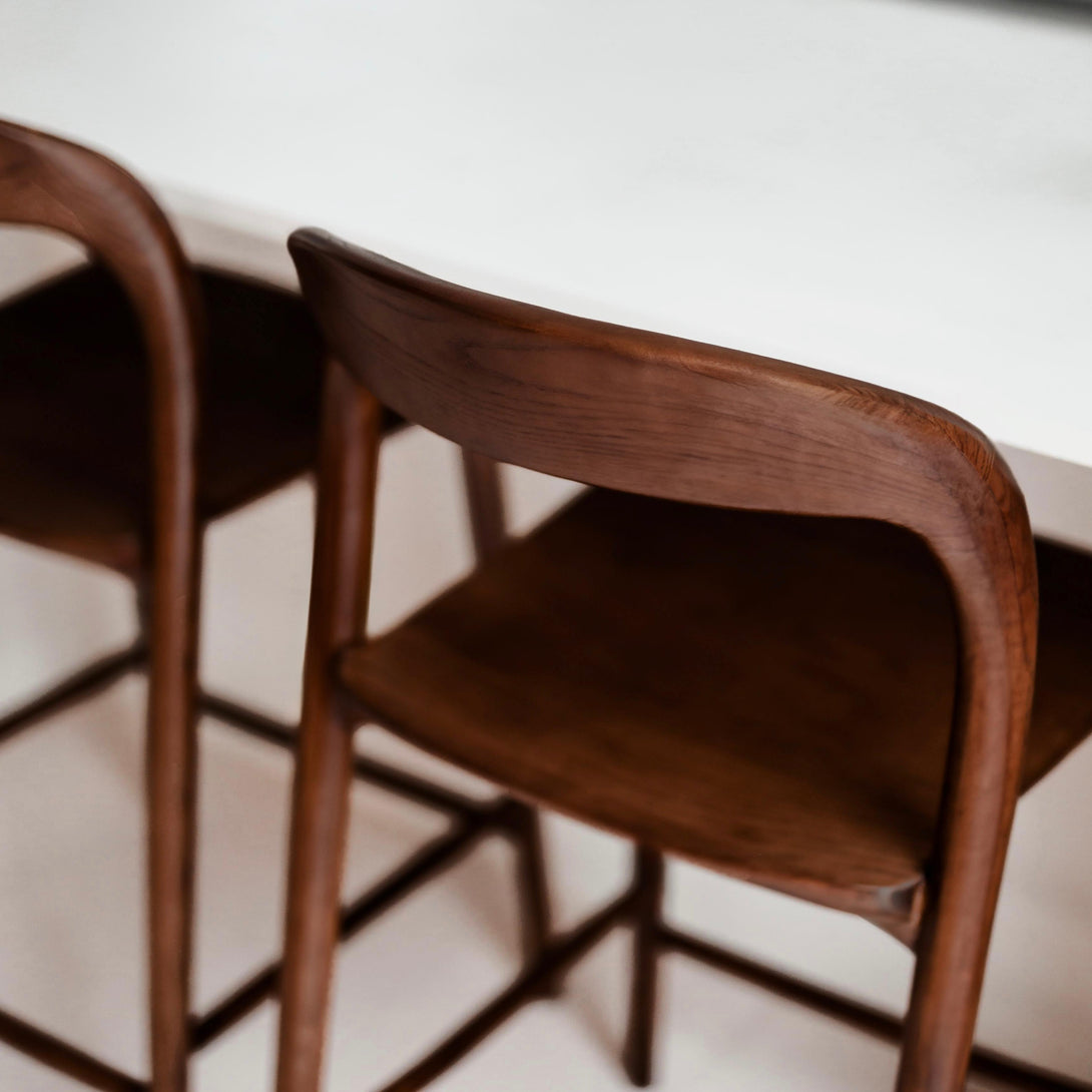 Close-up of the walnut wooden backrest of the Mowelli Nora bar stool at a kitchen island – Belgian designer furniture