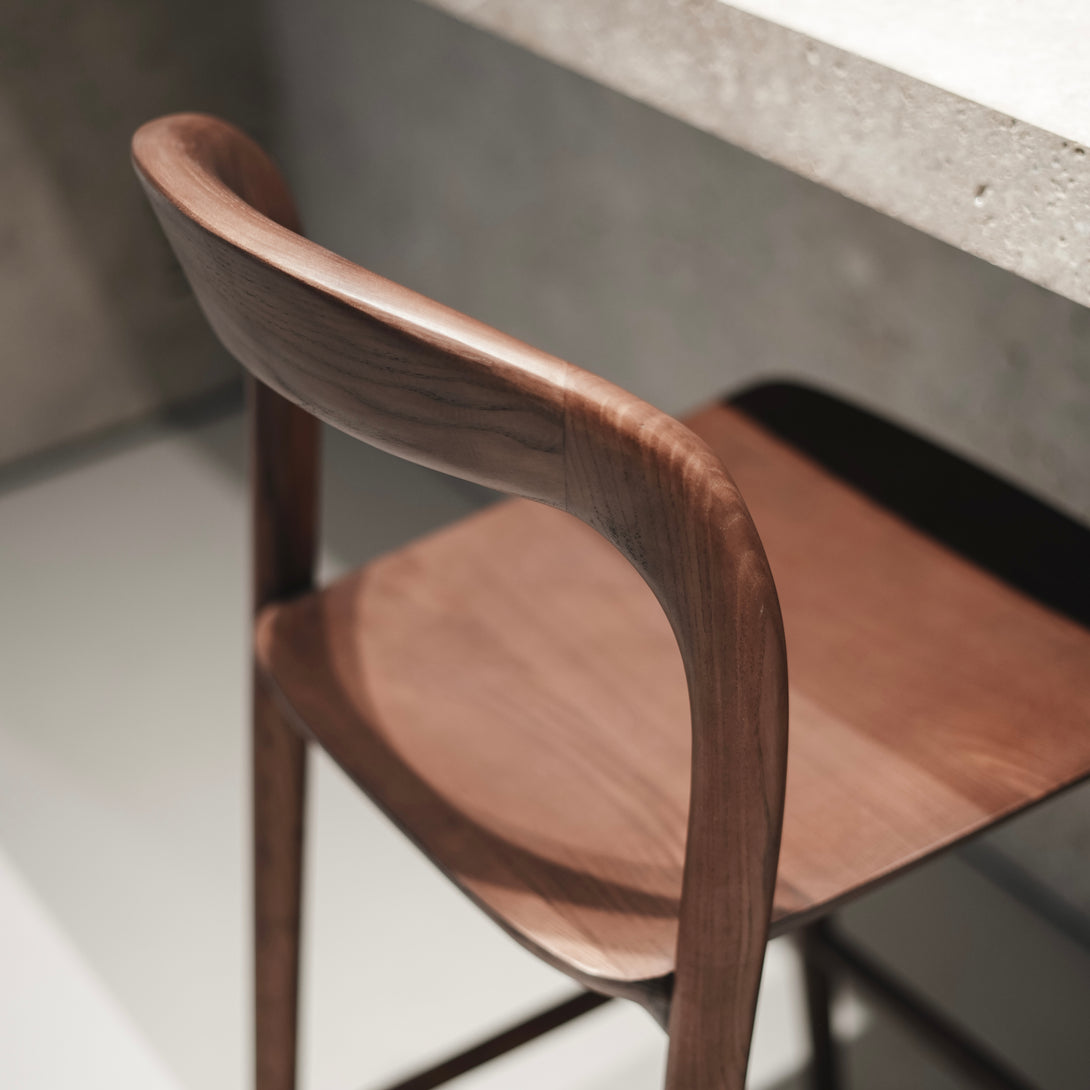 Detail view of Mowelli’s Nora bar stool in walnut – ergonomic wooden backrest and seat