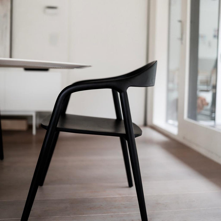 Side profile of the Mowelli Nora dining chair in black ash, displaying its sleek, sculpted frame.
