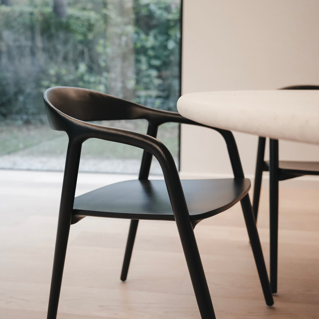 Side view of the black Nora dining chair by Mowelli in a minimalist dining room.
