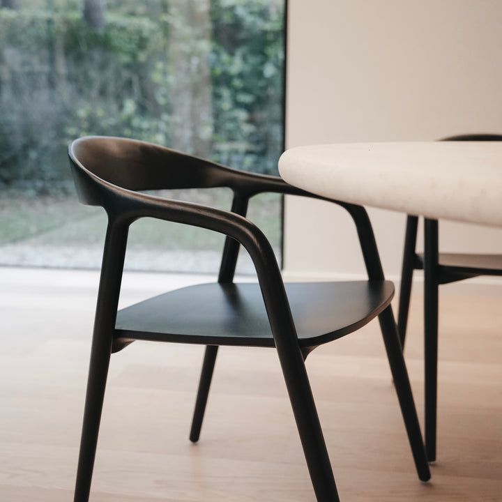 Side view of the black Nora dining chair by Mowelli in a minimalist dining room.