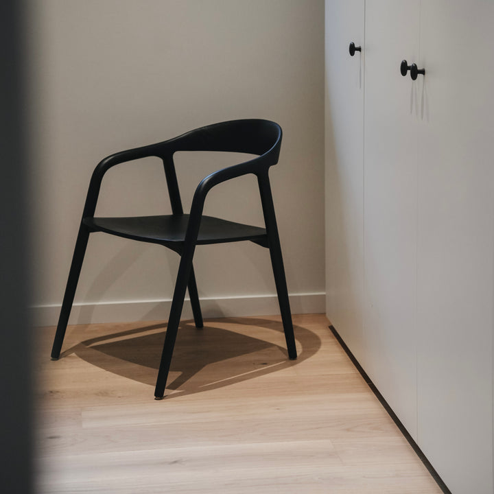 Black Nora dining chair by Mowelli with solid wooden frame in minimalist setting