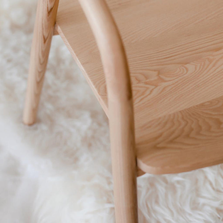 Close-up on the ash wood seat and leg of the Nora dining chair by Mowelli, showing its fine grain and soft finish.