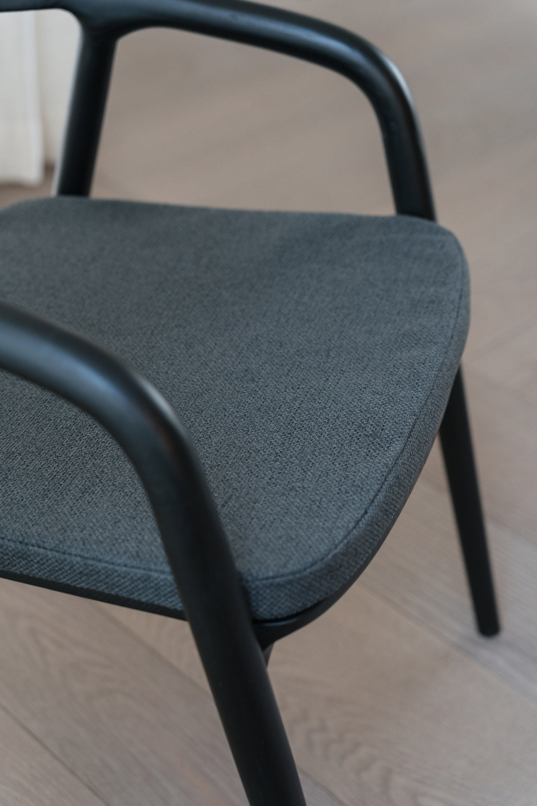 A black Nora dining chair by Mowelli with a charcoal black pillow