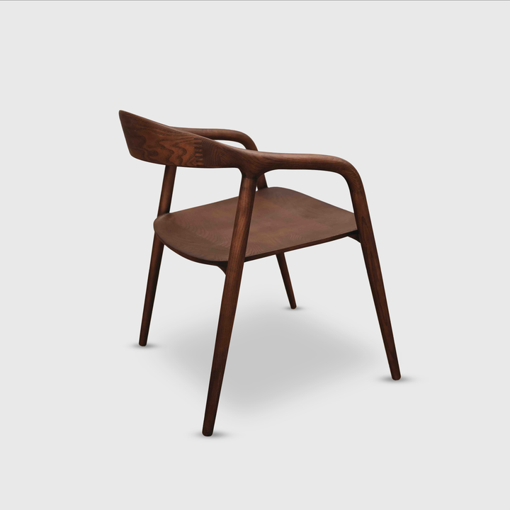 Walnut Nora dining chair by Mowelli with ergonomic backrest and contemporary wooden frame on a white background