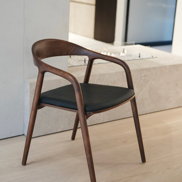Nora leather seating chair by Mowelli with black leather seat and walnut colour wood frame