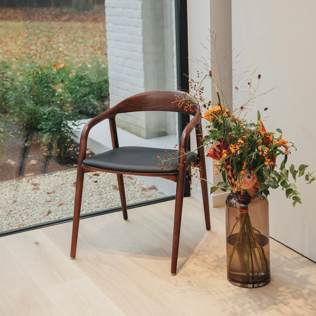 Front view of Nora leather seating chair by Mowelli featuring sustainable wooden frame and black leather seat.