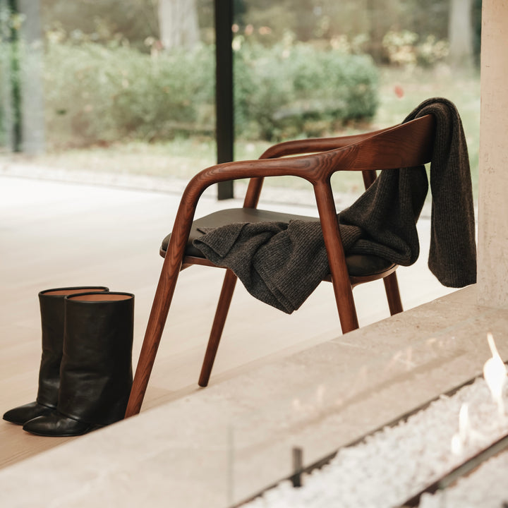 Side view of Nora leather seating chair by Mowelli with curved backrest and black leather seat, contemporary design. 