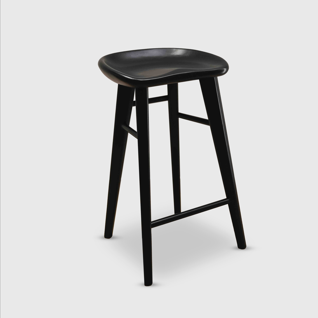 Cutout of Ollie bar stool by Mowelli in black ash wood, designed with a contoured seat and footrest.