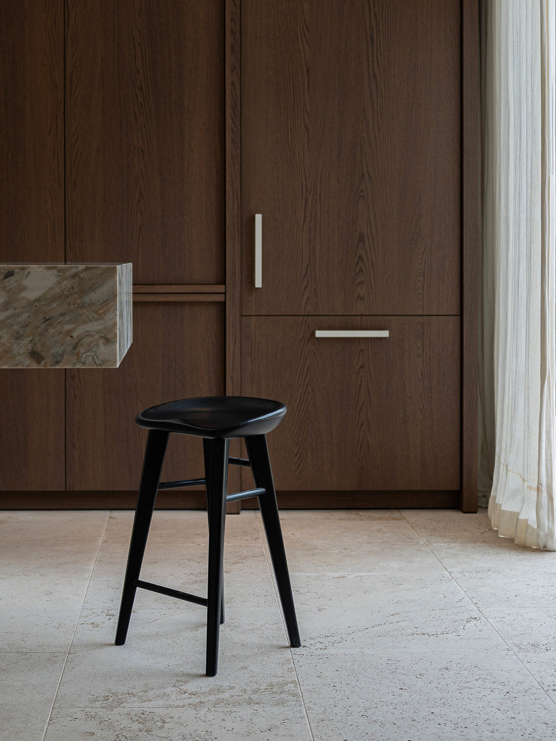 Ollie bar stool by Mowelli in charcoal black ash wood, styled at a kitchen counter with contemporary minimalist interiors.