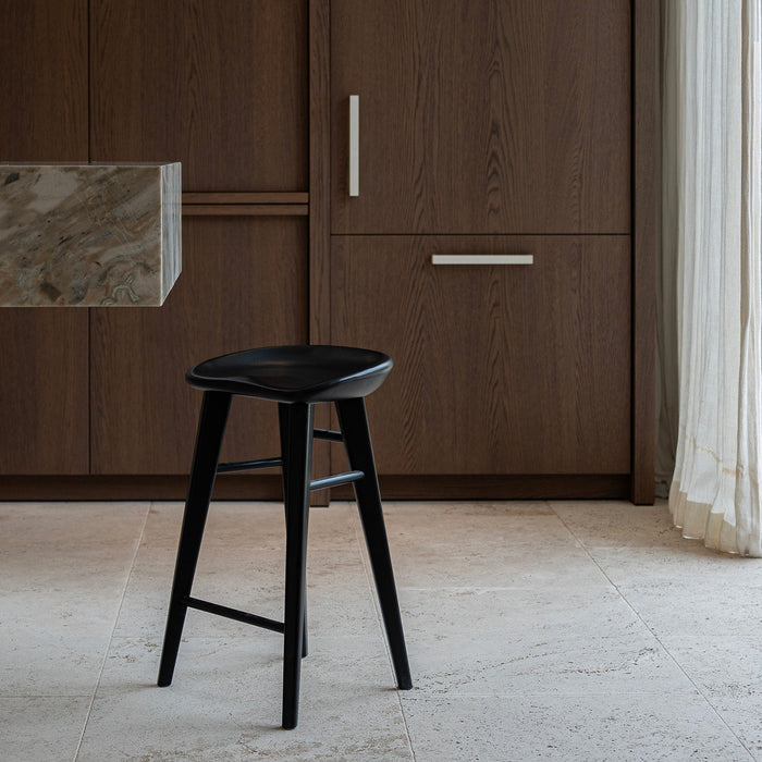 Ollie bar stool by Mowelli in charcoal black ash wood, styled at a kitchen counter with contemporary minimalist interiors.