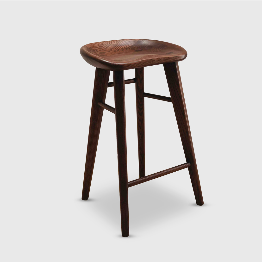 Cutout of Ollie bar stool by Mowelli in warm walnut wood, with smooth contours and elegant silhouette.