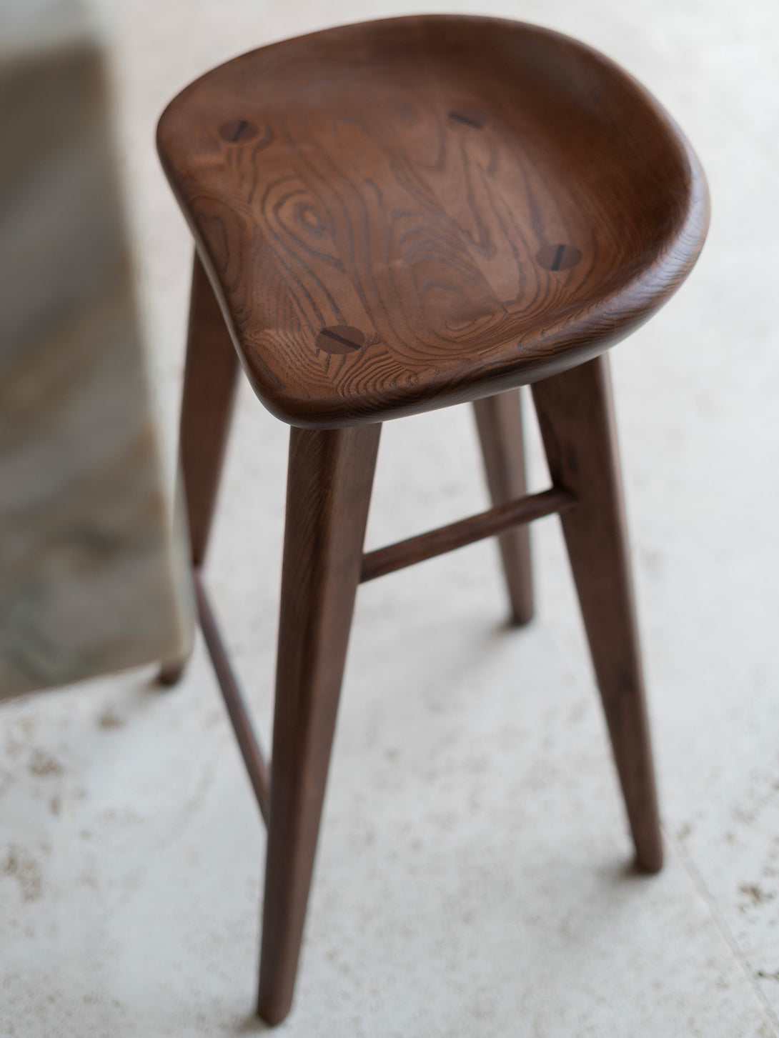 Close-up from above of Ollie bar stool in dark walnut finish by Mowelli