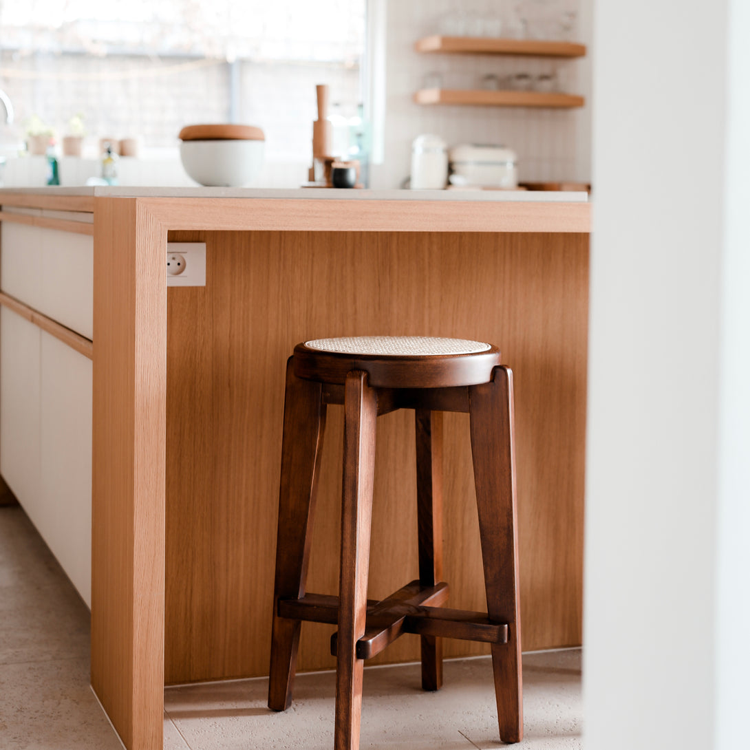 A walnut Pablo bar stool with rattan seat standing at a kitchen counter