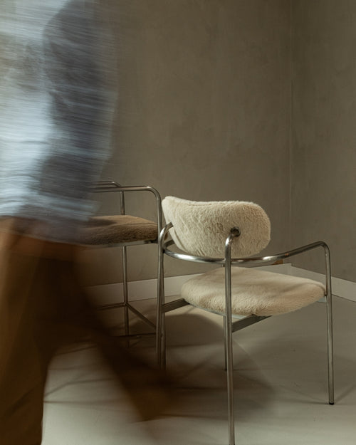 t4option0_0 | Coco dining chair with soft upholstered seat and stainless steel frame in a warm modern interior with motion blur