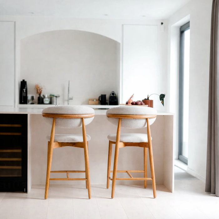Pair of Mowelli Dianne bar stools with a natural wooden frame and light beige upholstery at a modern kitchen counter