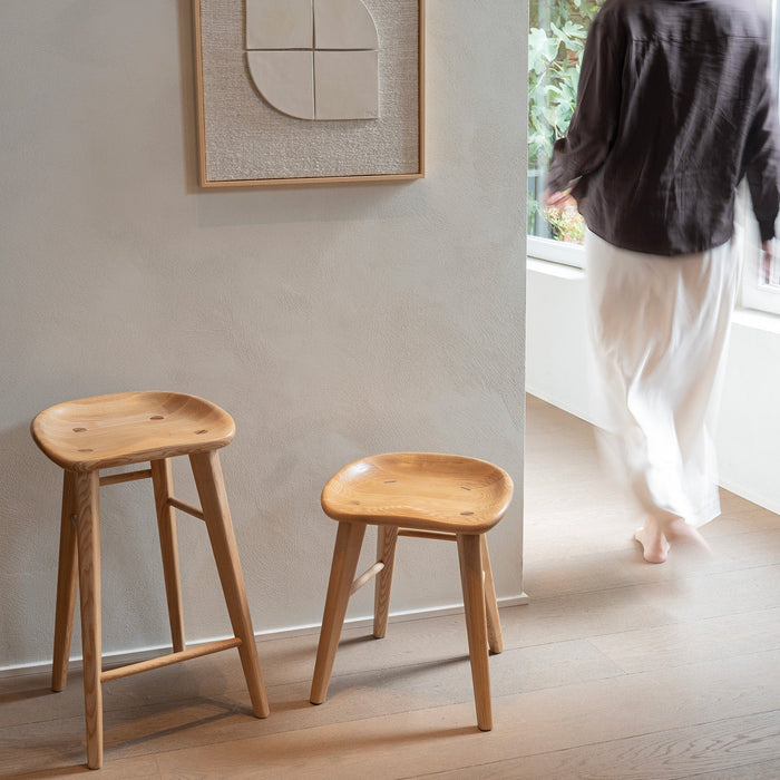 Two Ollie stools in natural oak — light wood finish with organic texture and smooth silhouette.